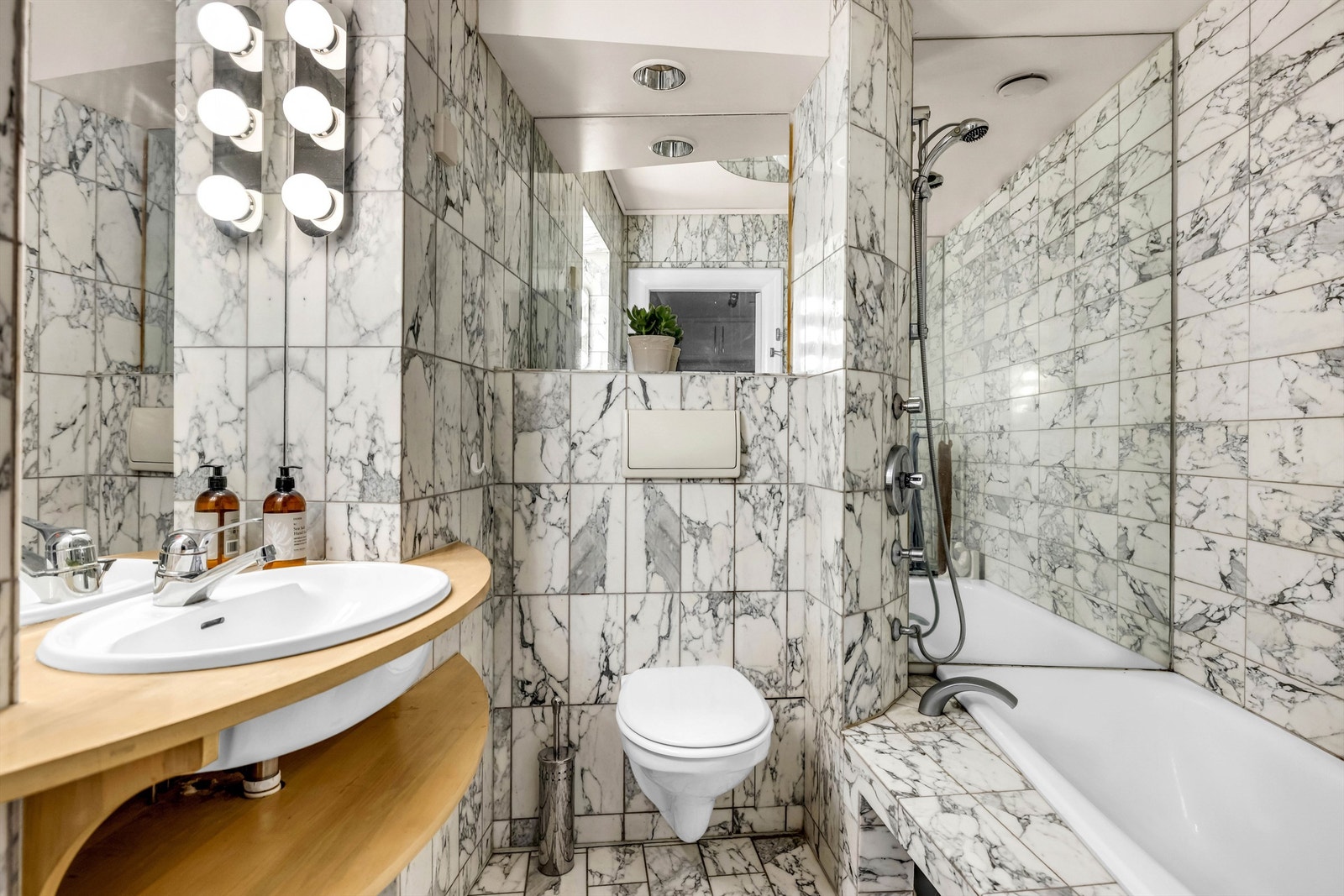 Badet er innredet med vegghengt toalett og badekar med armatur som er tilkoblet hånddusj. Galleribilde