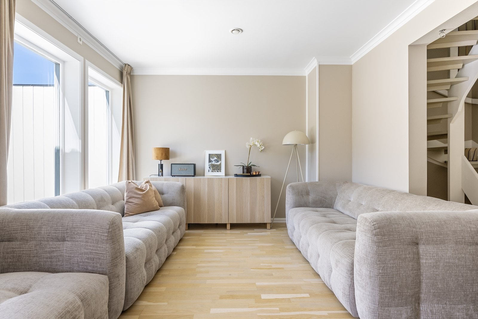 Stuen har god plass til en romslig sofagruppe. Trappen i malt treverk leder opp til andre etasje. Galleribilde