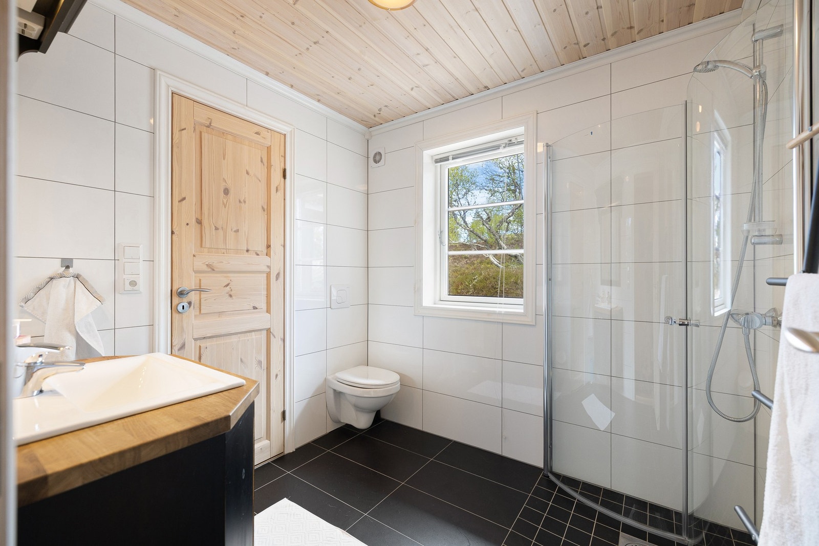 Bad med flislagte gulv og vegger, samt panel i himling. Gulvet er utstyrt med varmekabler, og rommet har mekanisk avtrekk via elektrisk vifte. Galleribilde