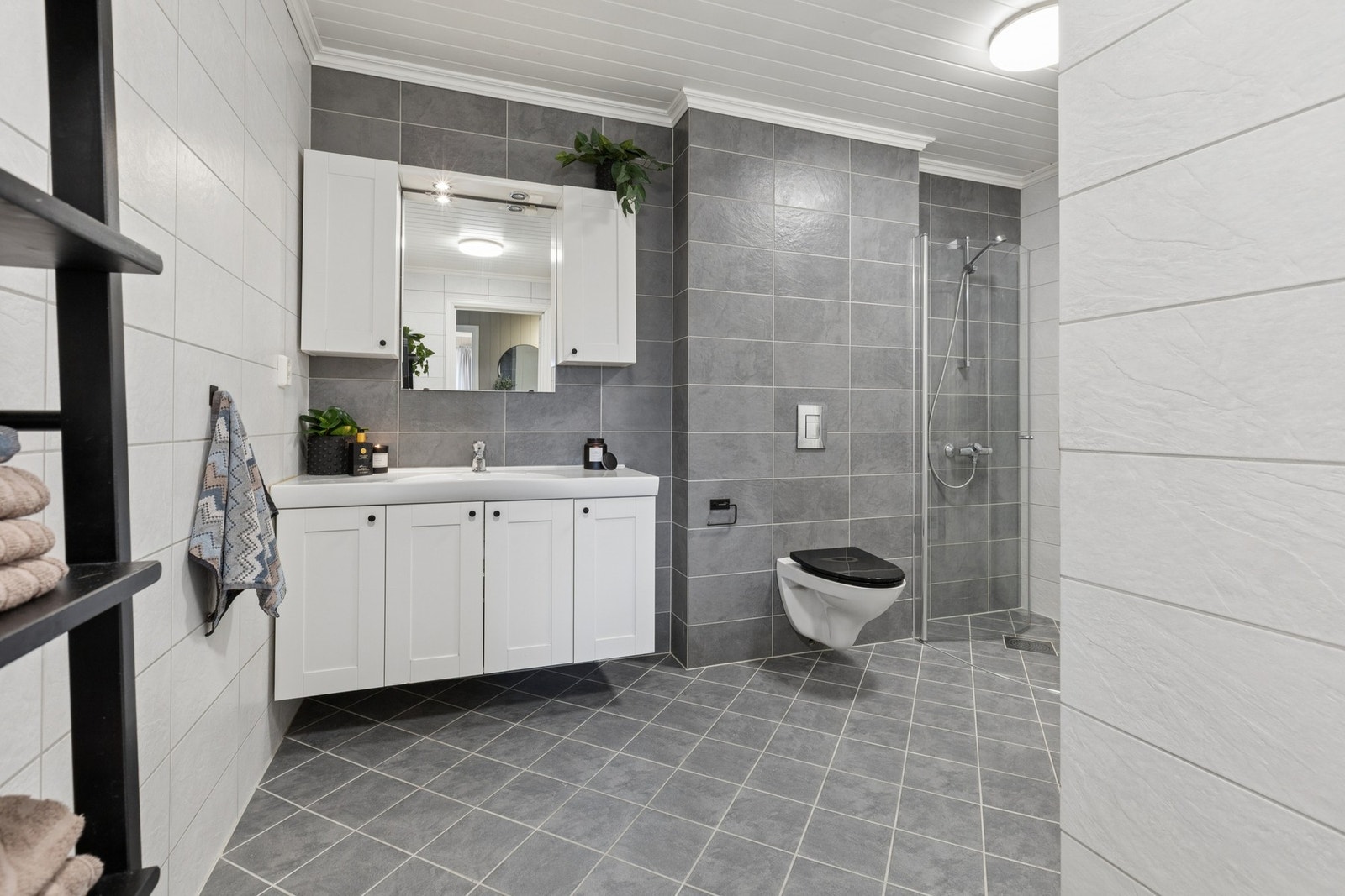Badet har en romslig og praktisk utforming med flislagte overflater og god gulvplass. Galleribilde