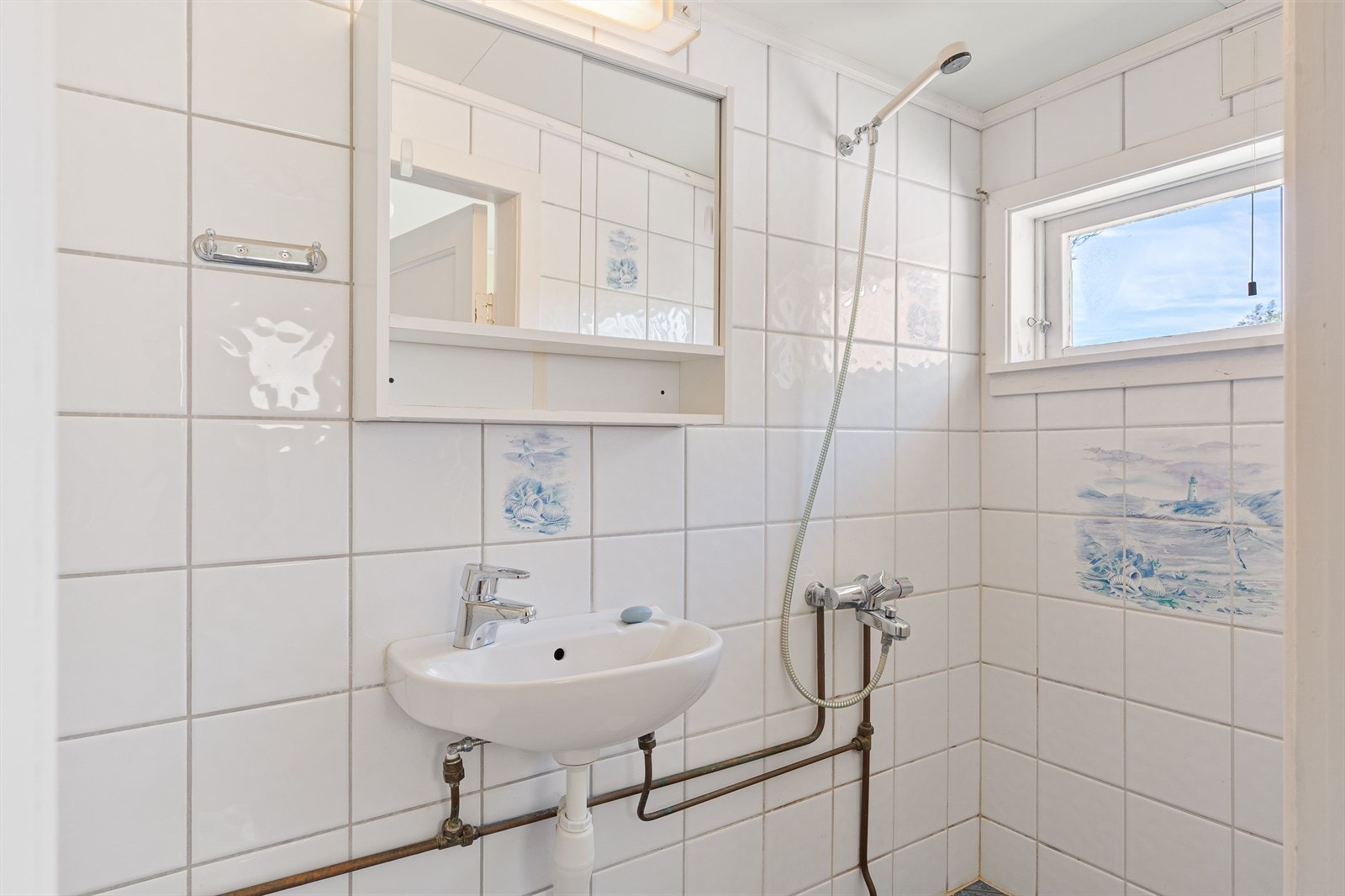 Badet er enkelt innredet rom med dusj, servant, speilskap og wc. Galleribilde