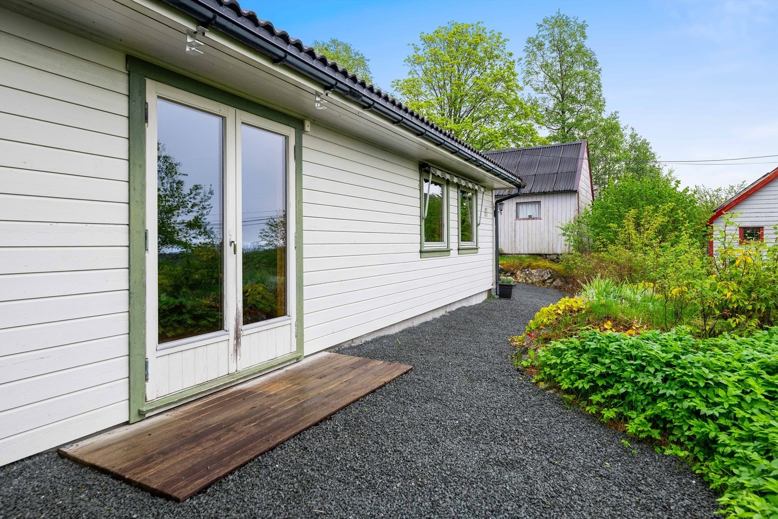 Tomten er opparbeidet med grus og diverse beplantning. Galleribilde