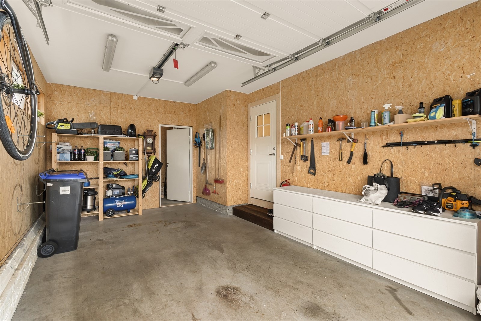 Garasjen har støpt betonggulv og god oppbevaringsplass på vegghyller og i skap. Galleribilde