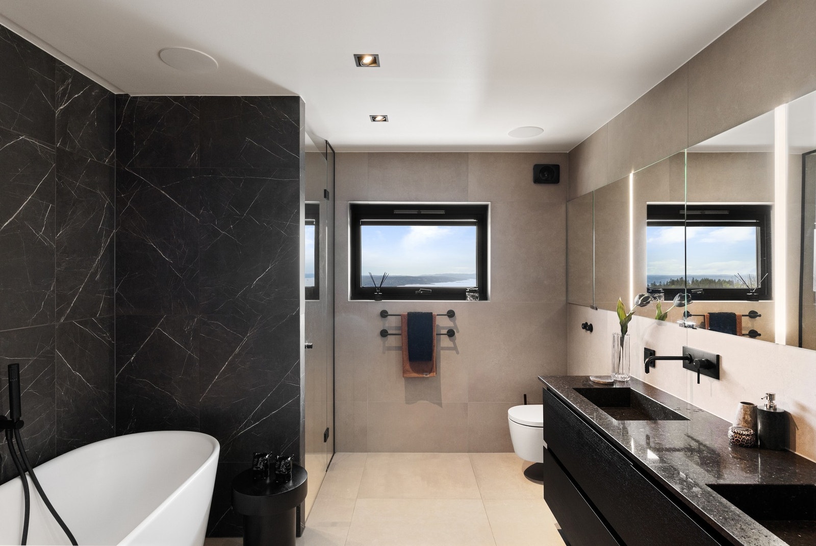 Badet fremstår som eksklusivt, moderne og spa-inspirert med store 80 x 80 cm fliser i ulike utførelser på vegger og gulv, samt behagelige varmekabler. Galleribilde