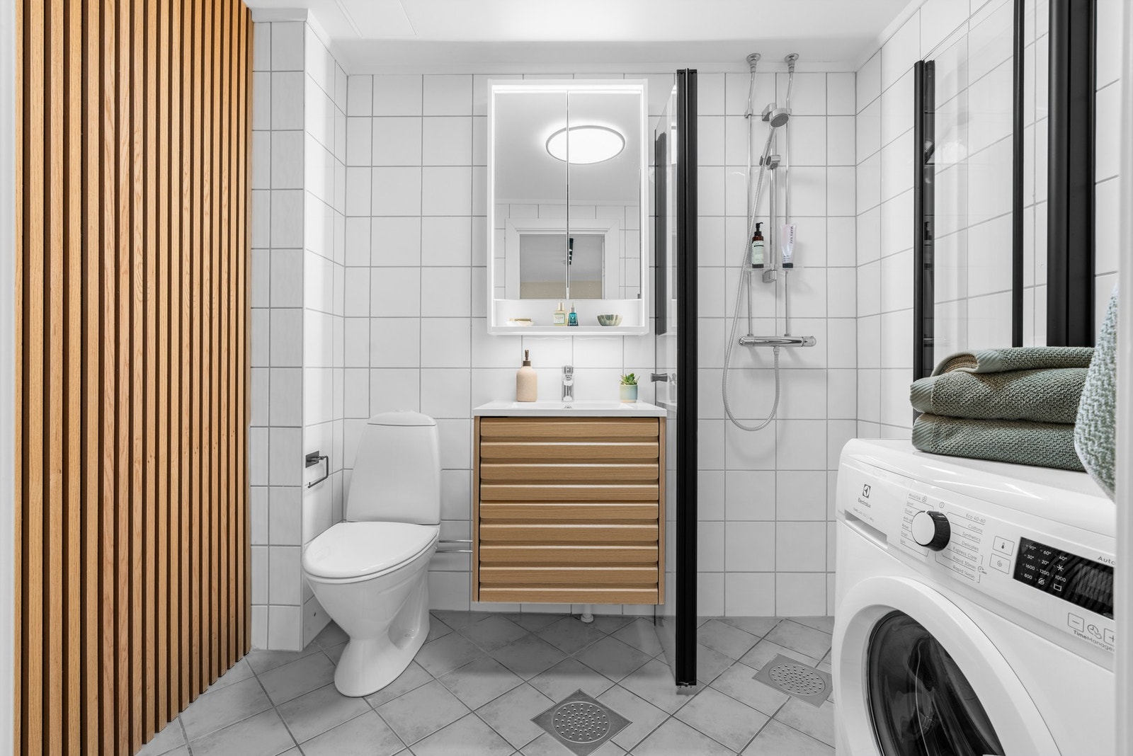 Badet ble modernisert av borettslaget i 2005 og oppgradert i 2024 med ny servant, underskap, dusjdører i glass og dekorativ spilevegg. Galleribilde