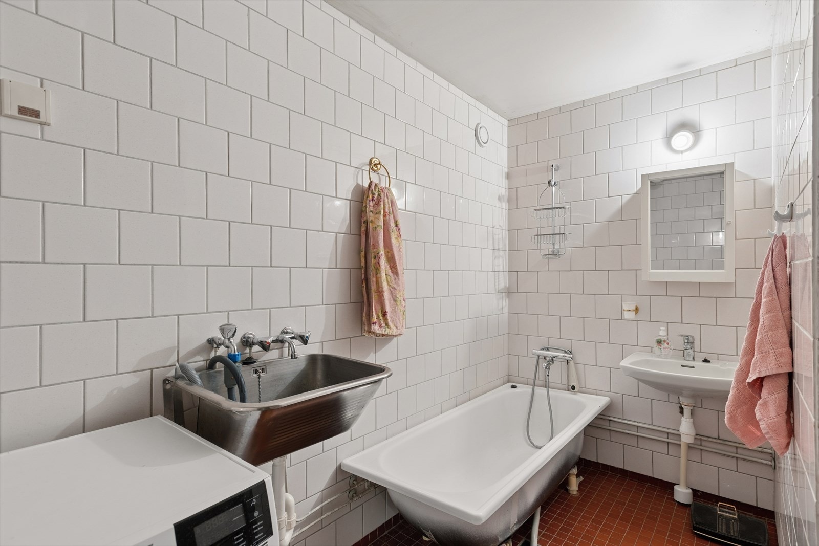 Eldre, flislagt bad utstyrt med badekar og opplegg for vaskemaskin. Rommet har mekanisk avtrekk. Galleribilde