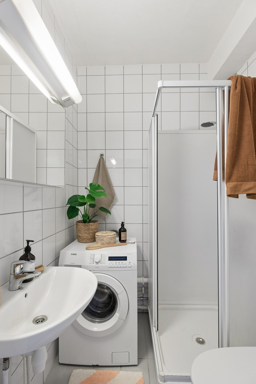 Flislagt bad med dusjkabinett, servant og opplegg for vaskemaskin. Galleribilde