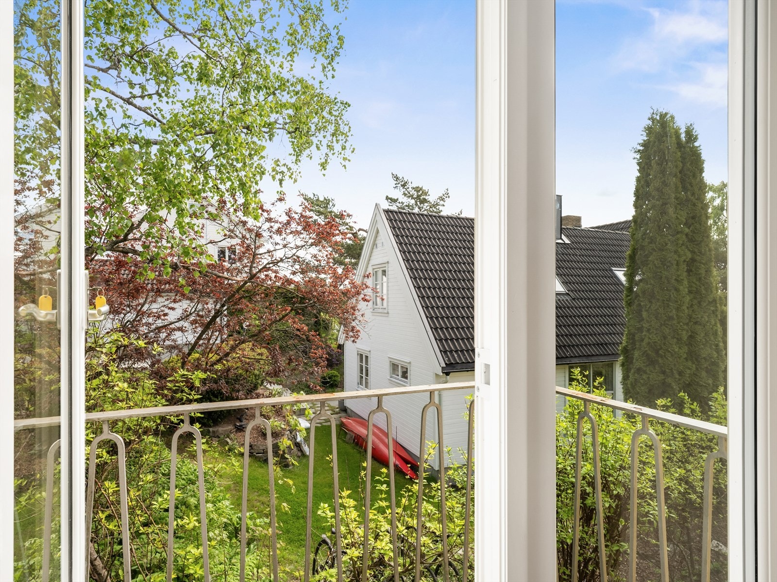 Balkongen har metall rekkverk, med utsikt over hagen og det hyggelige nabolaget. Galleribilde
