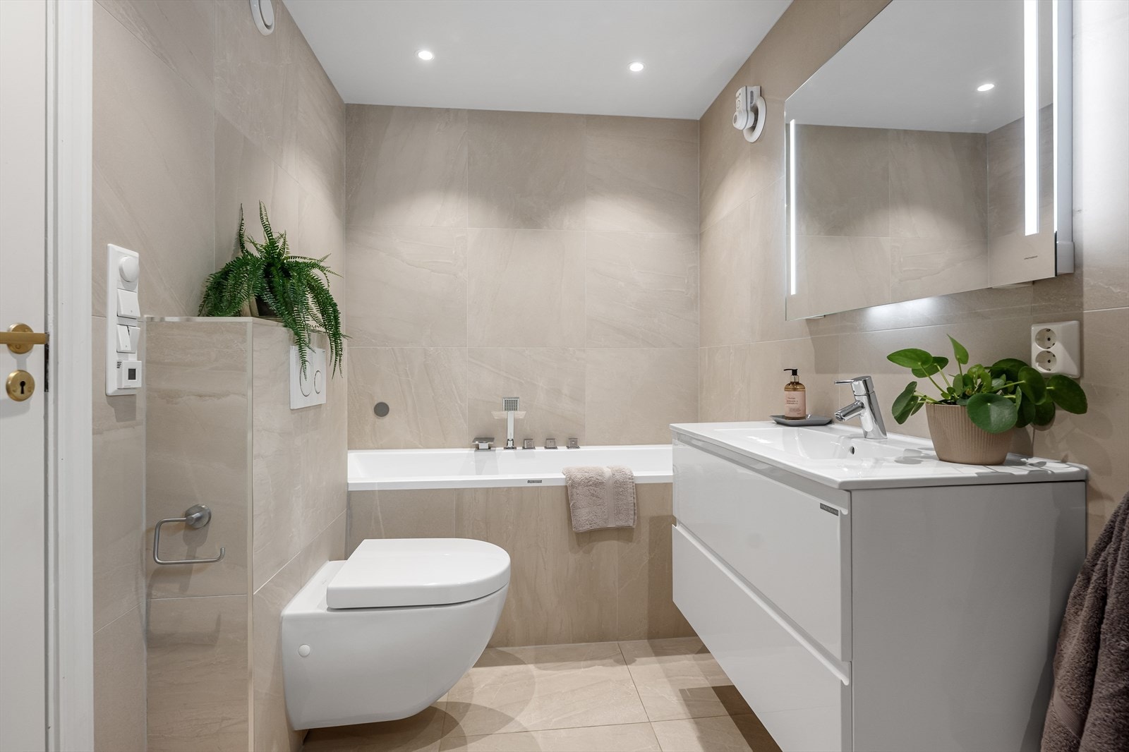 Badet er utstyrt med både innfliset badekar og vegghengt toalett med innebygget sisterne. Galleribilde