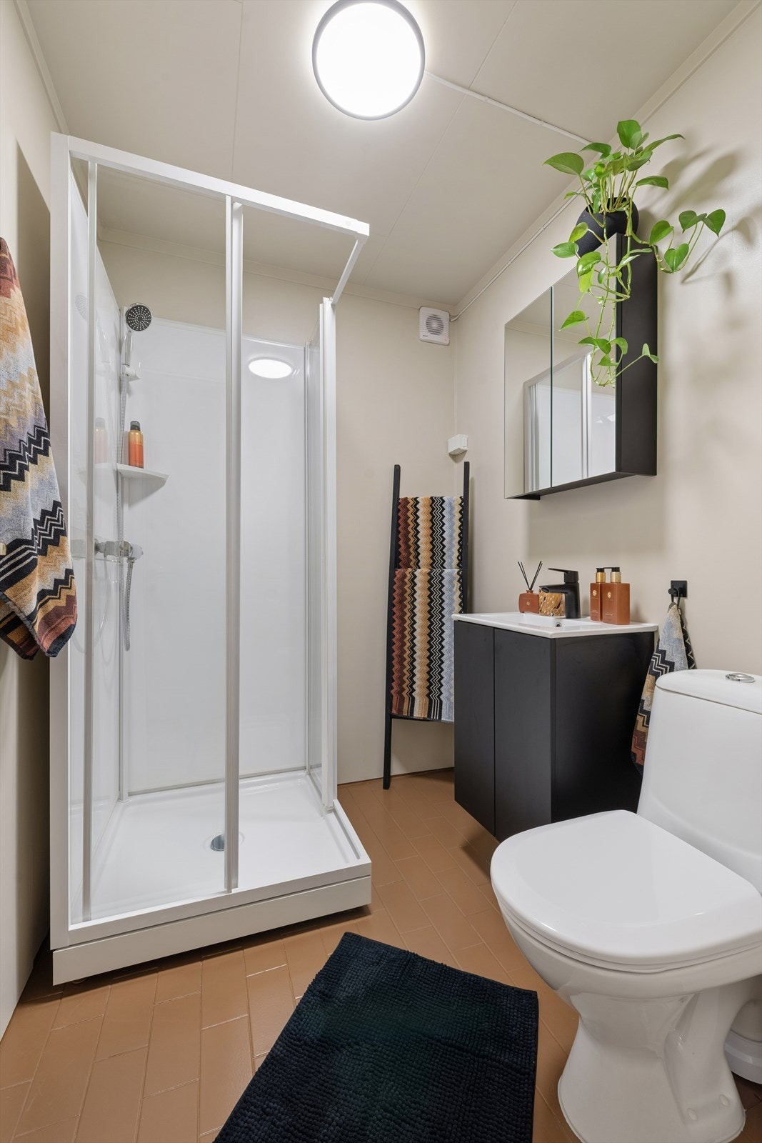 Badet er utstyrt med toalett, dusjkabinett, baderomsinnredning med servant og speilskap. Galleribilde