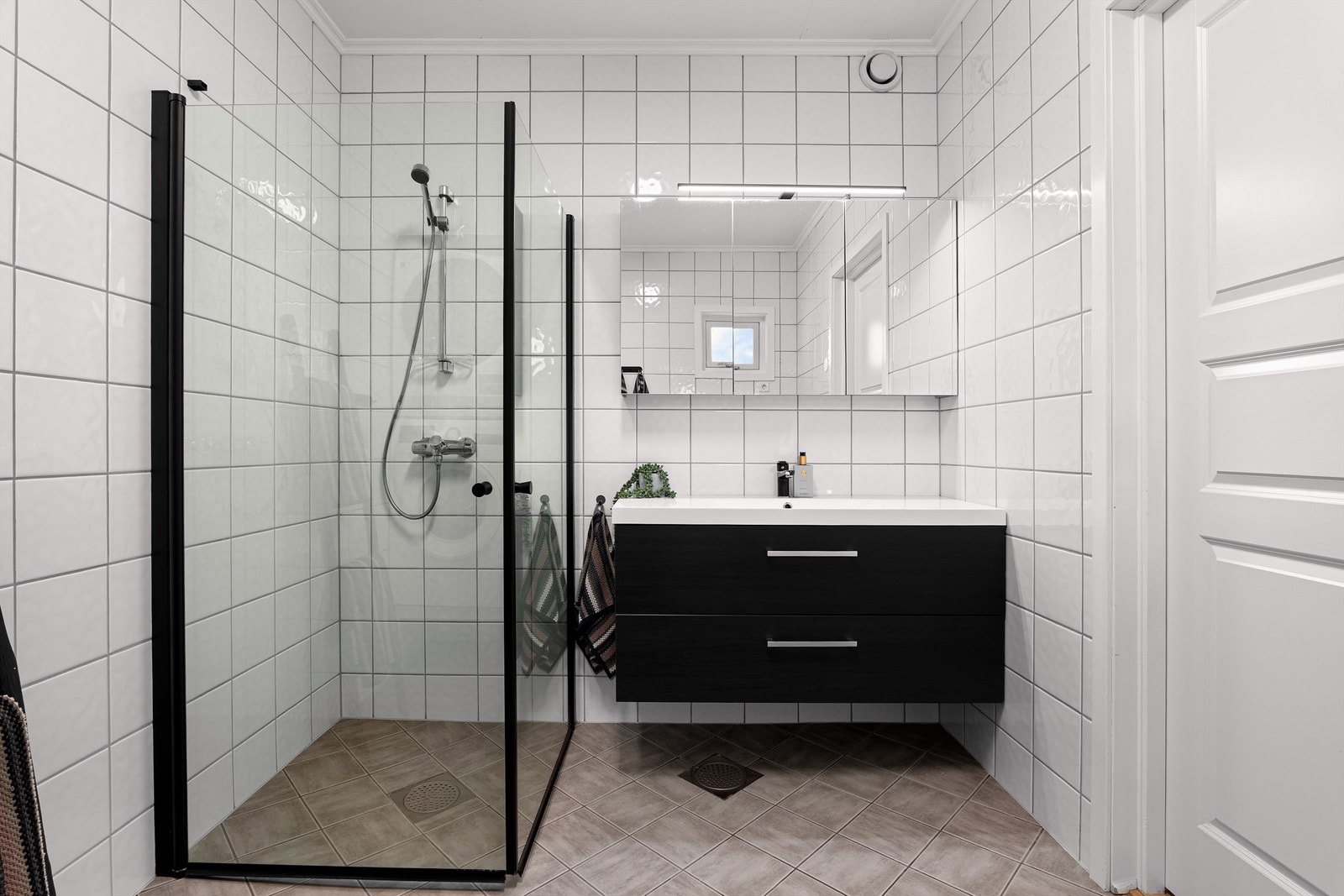 Badet er fra byggeåret, men oppgradert med blant annet moderne baderomsmøbler og dusjhjørne med tidsaktuelle sorte profiler. Galleribilde