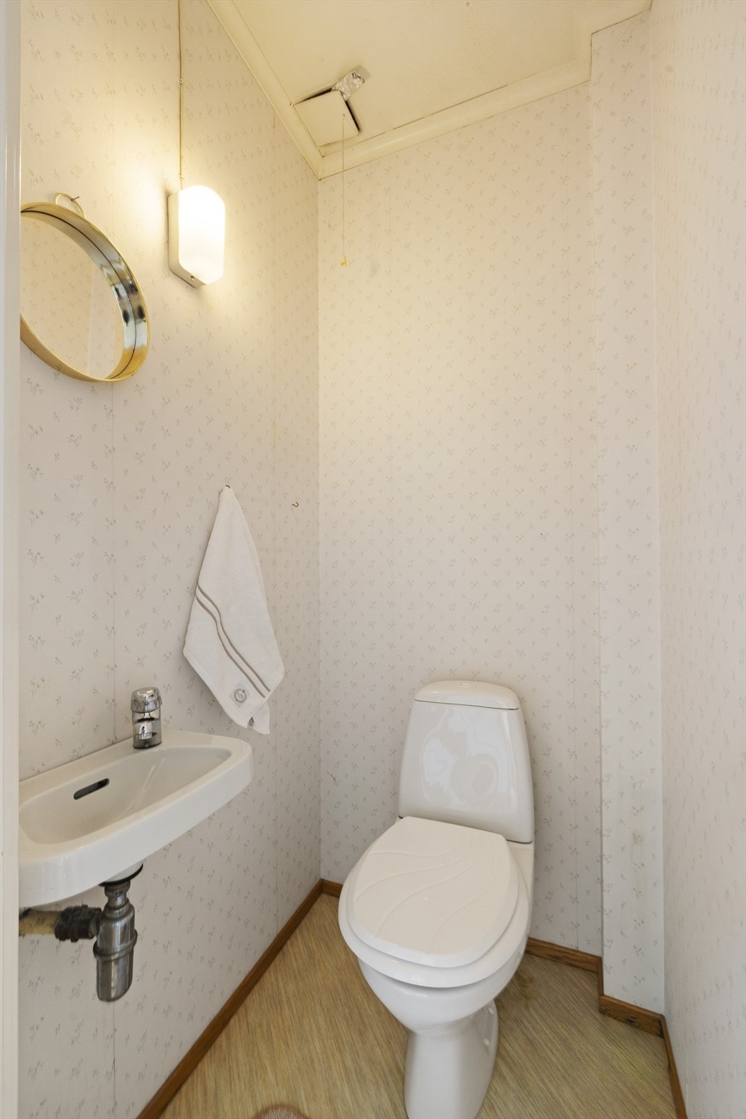 Vegg i vegg med baderommet finner man et toalettrom innredet med belegg på gulv og tapetserte vegger. Rommet er ellers utstyrt med toalett og servant. Galleribilde