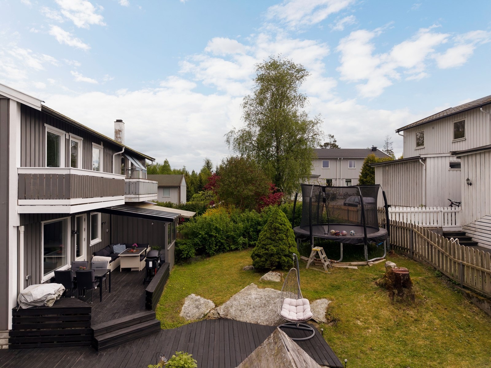 Oversiktsbilde av eiendommen viser en velholdt hage og terrasseområde. Galleribilde