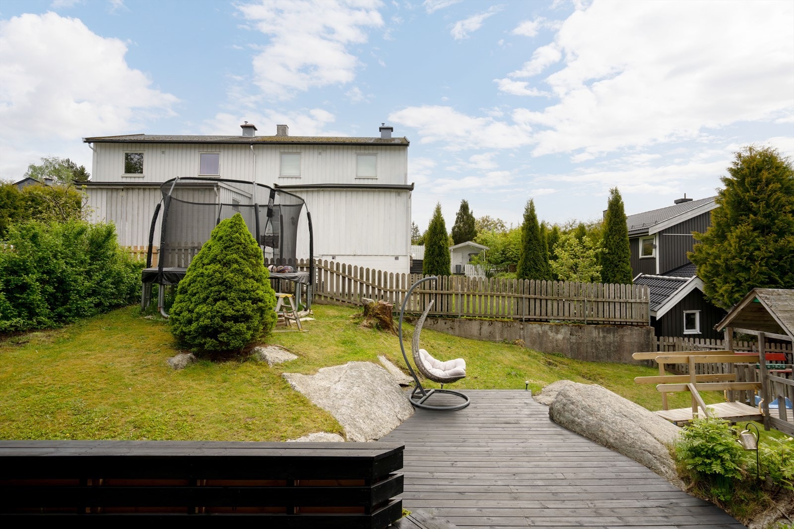 Den private hagen er innrammet av gjerder og inkluderer lekeområder for barn. Galleribilde