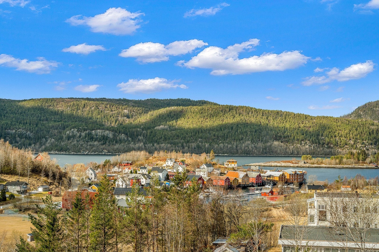Nydelig utsikt over fjorden og den sjarmerende bryggerekka i Råkvåg - et idyllisk område med maritim atmosfære og vakre omgivelser. Galleribilde