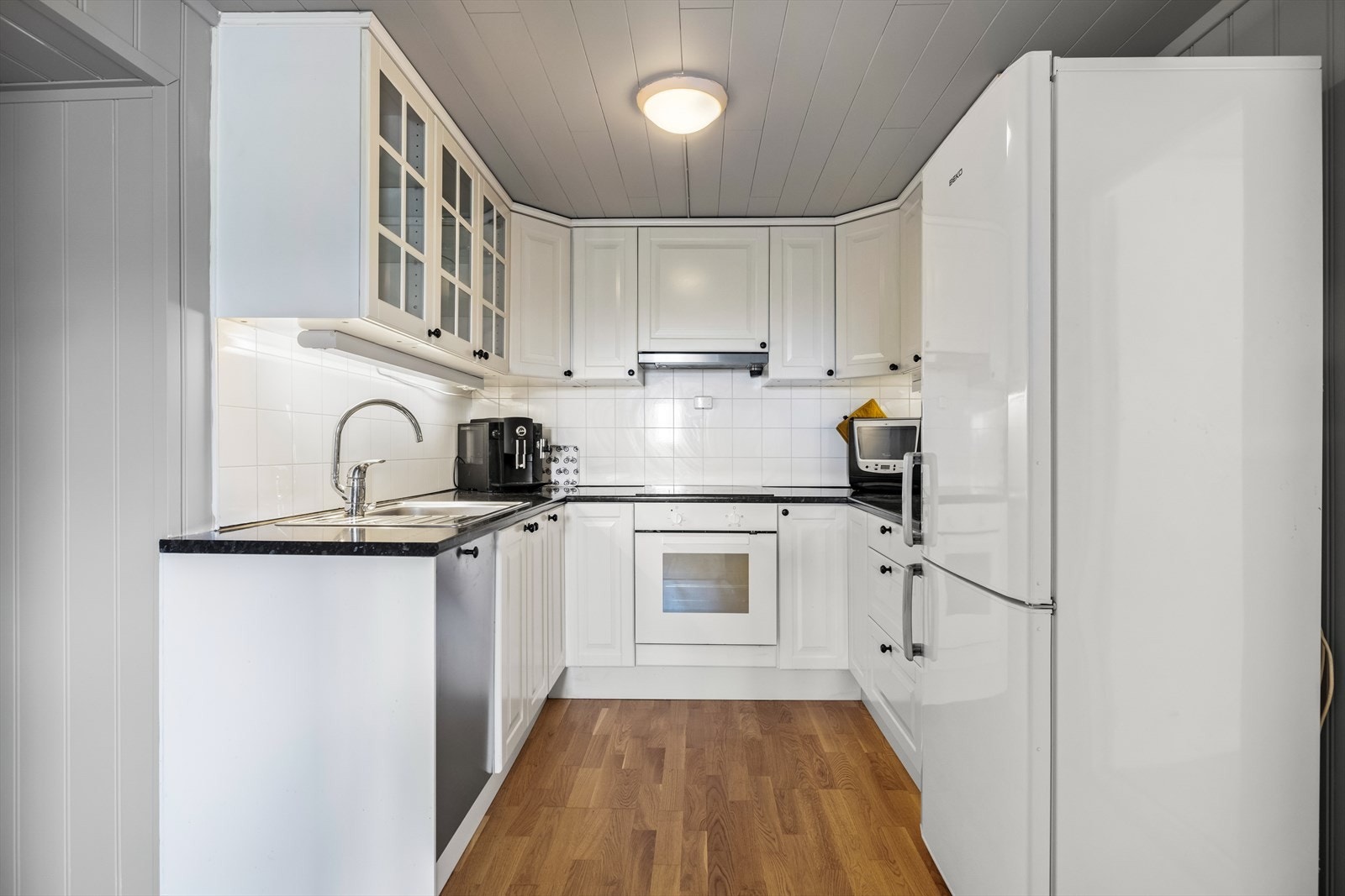 Kjøkkenet har innredning med lyse, profilerte fronter og laminat benkeplate med kum. Galleribilde