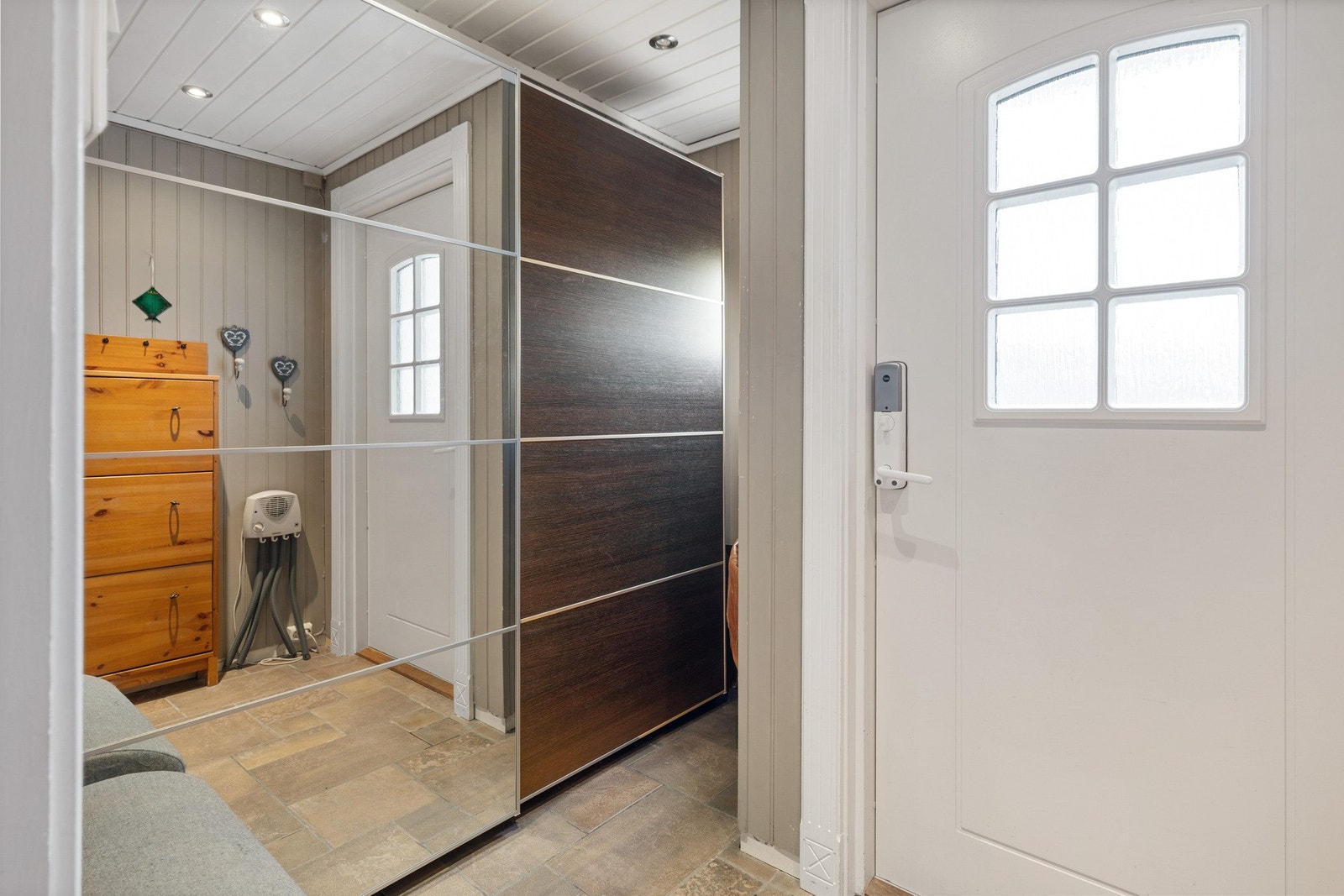 Romslig entré med skyvedørsgarderobe og flislagt gulv med varmekabler. Galleribilde