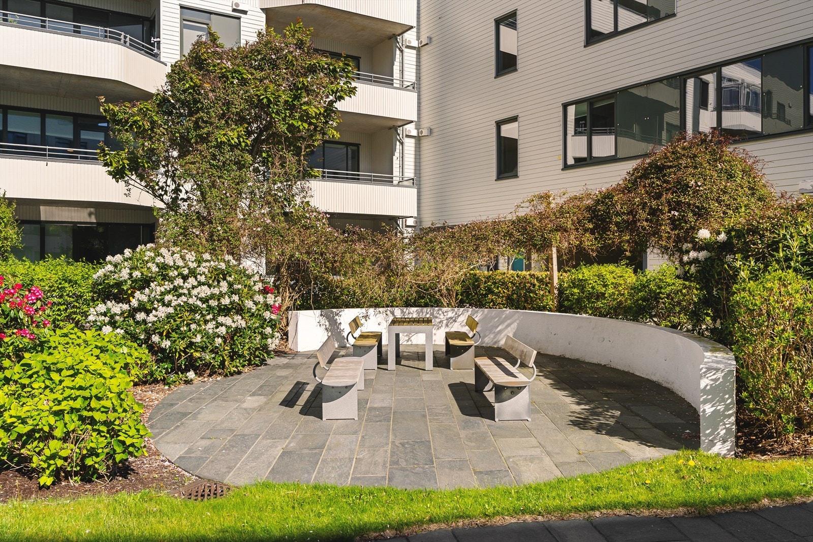 Pent opparbeidet uteområder med grønne plener, fargerike blomsterbed og hyggelige oppholdssted for beboerne Galleribilde