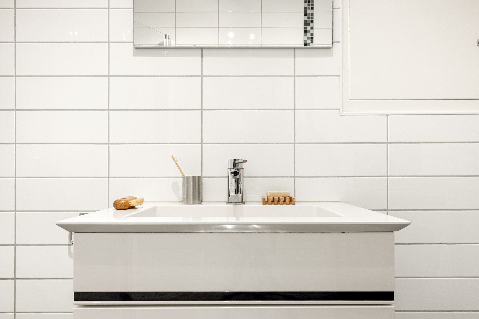 Badet er innredet med vegghengt toalett, dusj med glassvegger, og baderomsmøblement med speil og belysning. Galleribilde