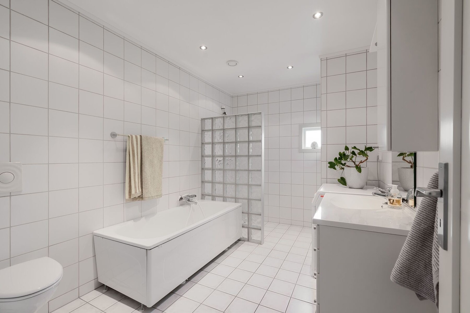Badet byr på både dusj og badekar samt vegghengt toalett, opplegg for vaskemaskin, servant med innredning og downlights i himling. Galleribilde