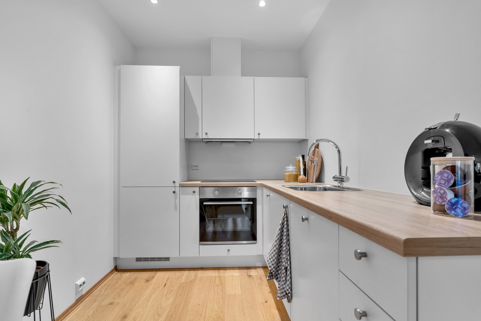 Innredningen er tidløs og elegant, med hvite, slette fronter og slitesterke laminerte benkeplater som balanserer funksjonalitet og moderne design. Galleribilde