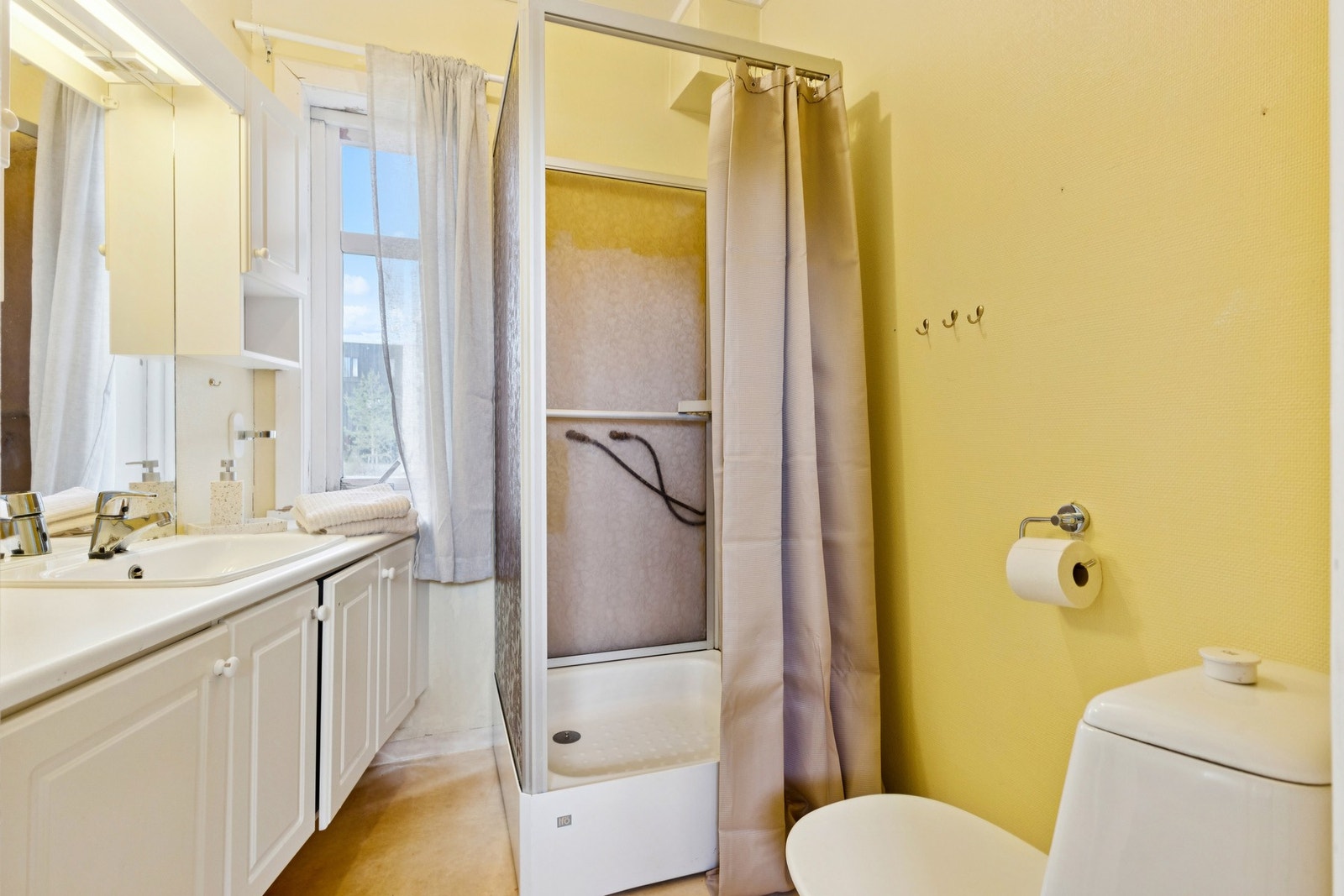 Badet til hoveddelen i denne etasjen er utstyrt med servantinnredning, overskap med speil og toalett, dusjkabinett og varmekabler i gulv. Galleribilde