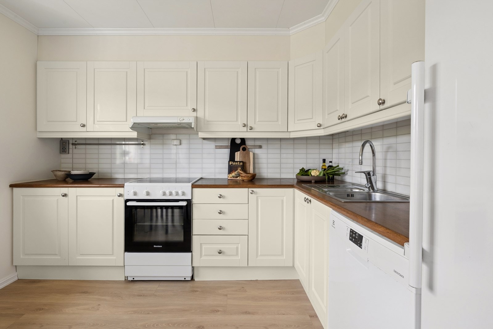 Kjøkkenet har innredning med profilerte fronter. Benkeplaten er av laminat. Kitchenboard på vegger mellom benkeplater og overskap. Det er avtrekk via balansert anlegg. Galleribilde