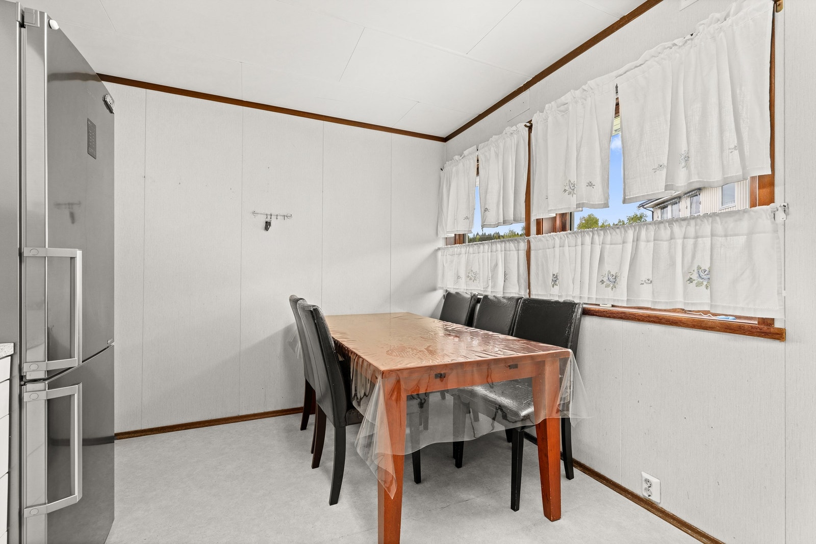 Det er fliser mellom kjøkkenbenk og overskap, og gulvbelegg på gulvet. Galleribilde