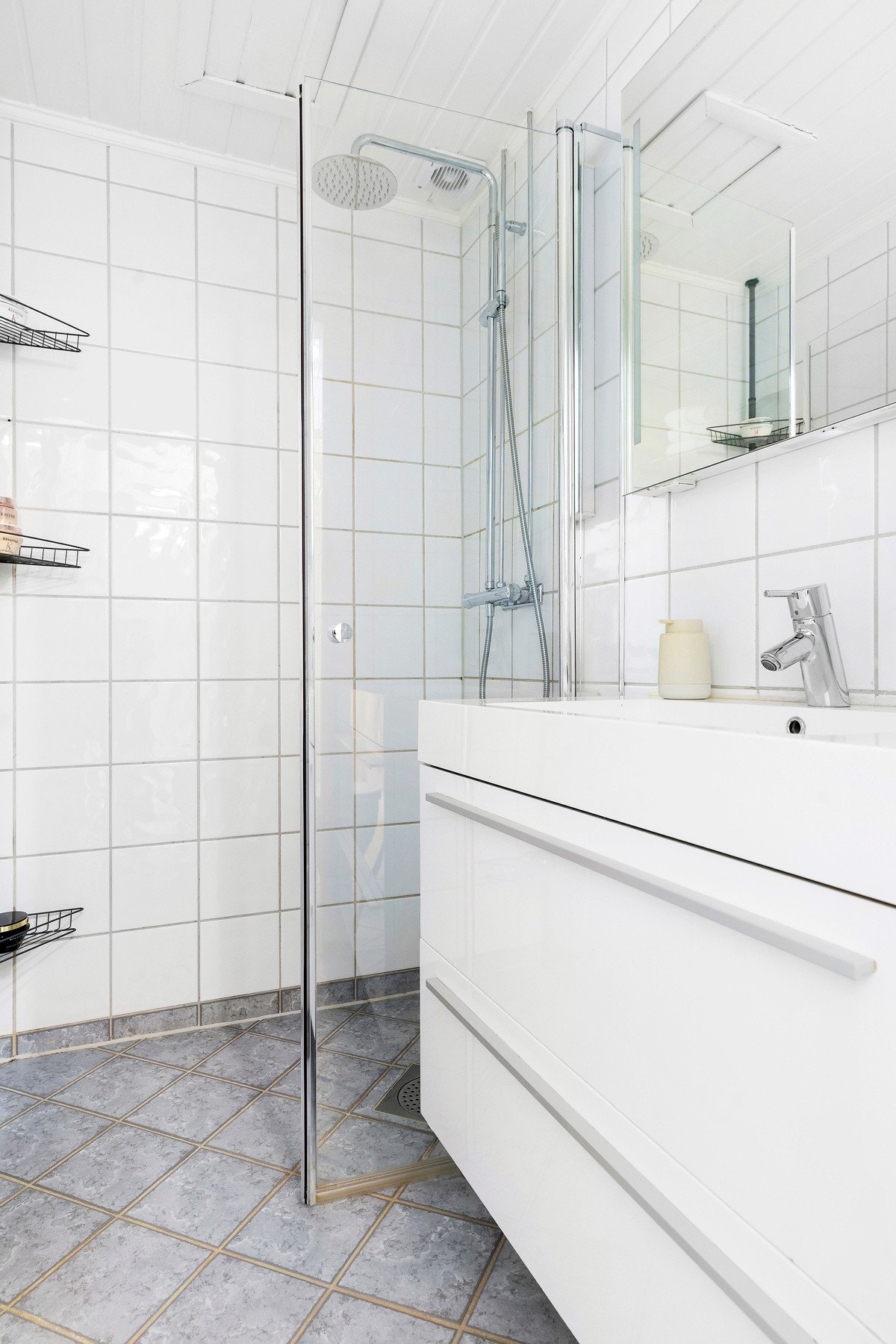 Baderomsinnredning bestående av benkeskap med profilerte fronter. Veggskap med speilfronter over servant. Galleribilde
