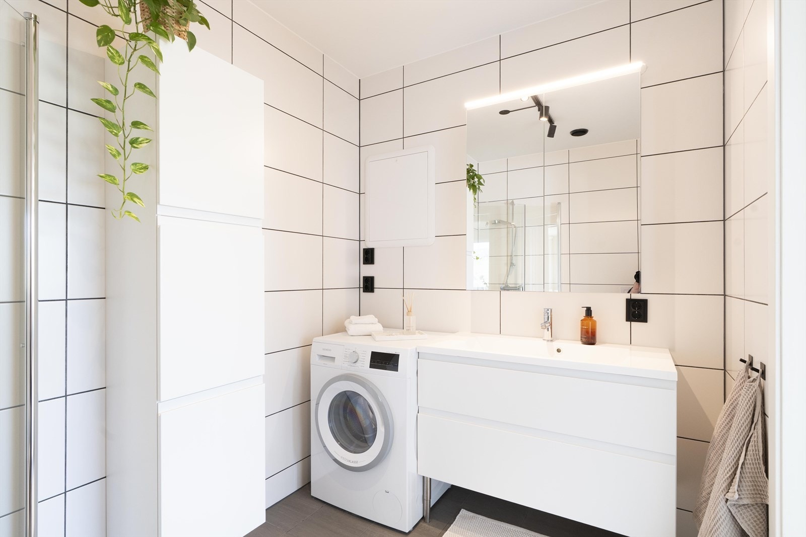 Det er også opplegg/plass til vaskemaskin, samt høyskap som gir praktisk oppbevaring. Badet har en ryddig og arealeffektiv utforming med et rent og tidløst uttrykk. Galleribilde