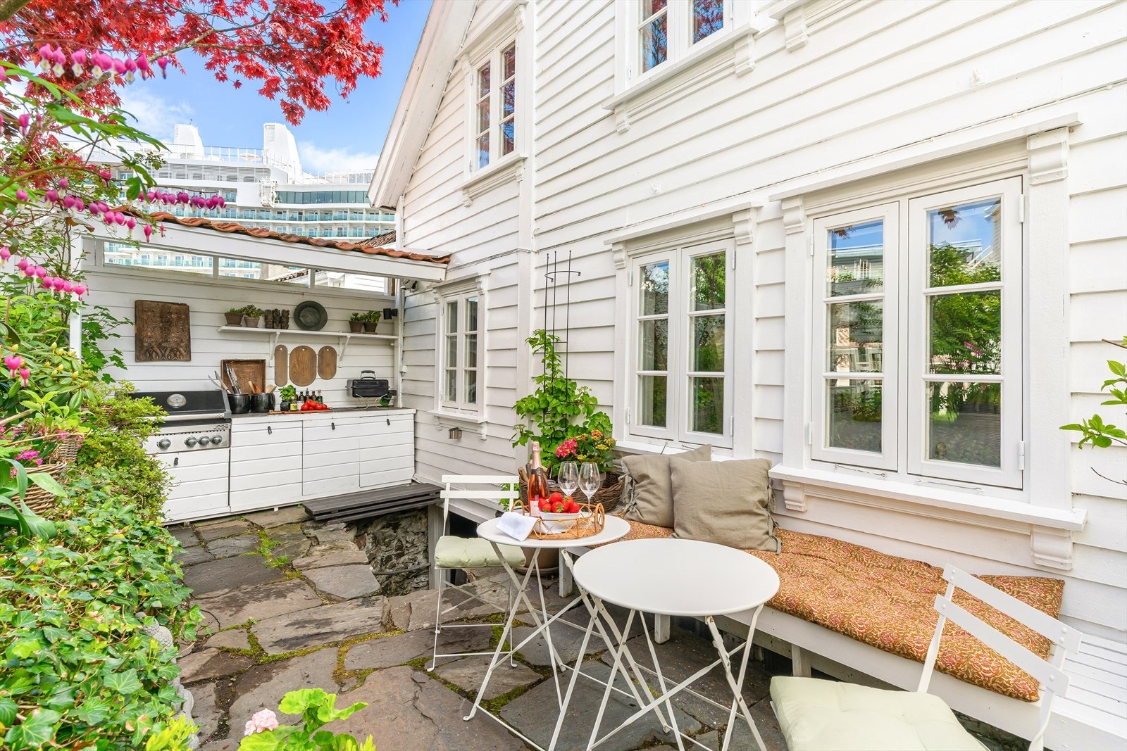 Uteplass med spesialtilpasset utekjøkken, grill og frodige omgivelser som legger til rette for hyggelige sommerdager og sosiale kvelder. Galleribilde