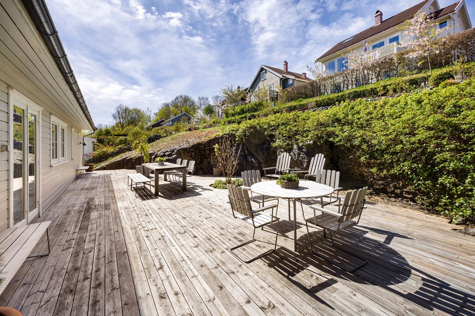 Terrassen har plass til både spisebord og loungemøbler, og er godt skjermet av hage og støttemurer rundt tomten. Galleribilde