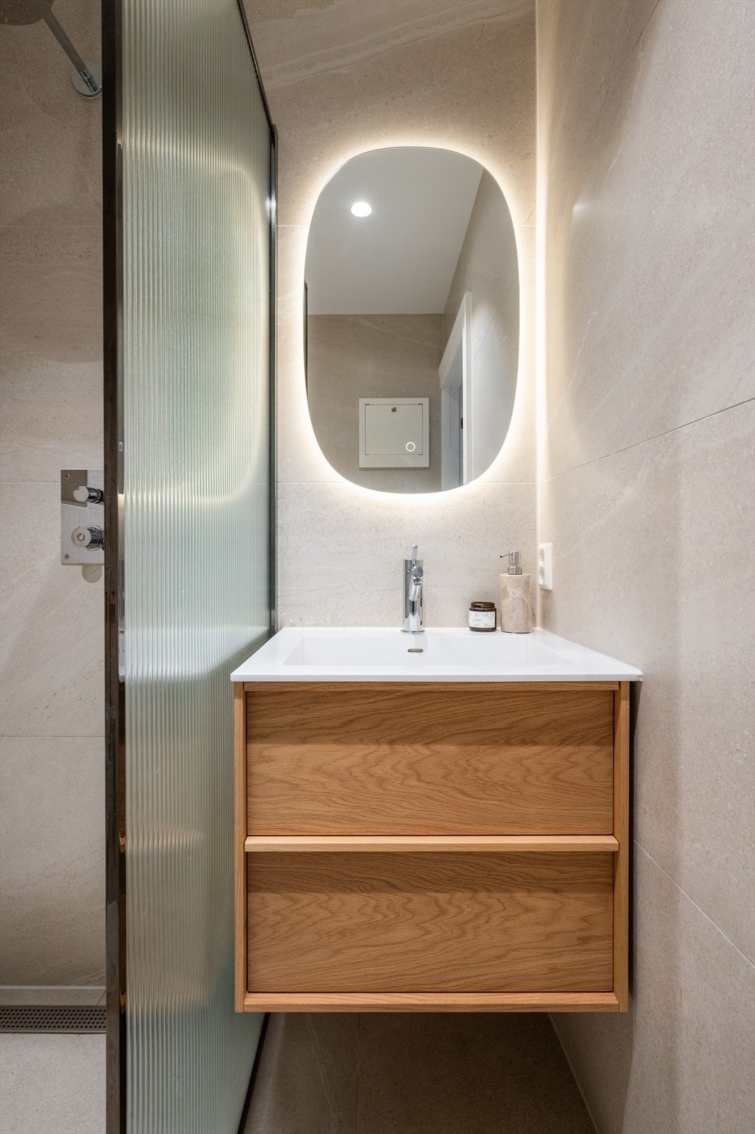 Badet er innredet med store, moderne fliser på gulv med varmekabler, flislagte vegger og malt himling med downlights. Galleribilde