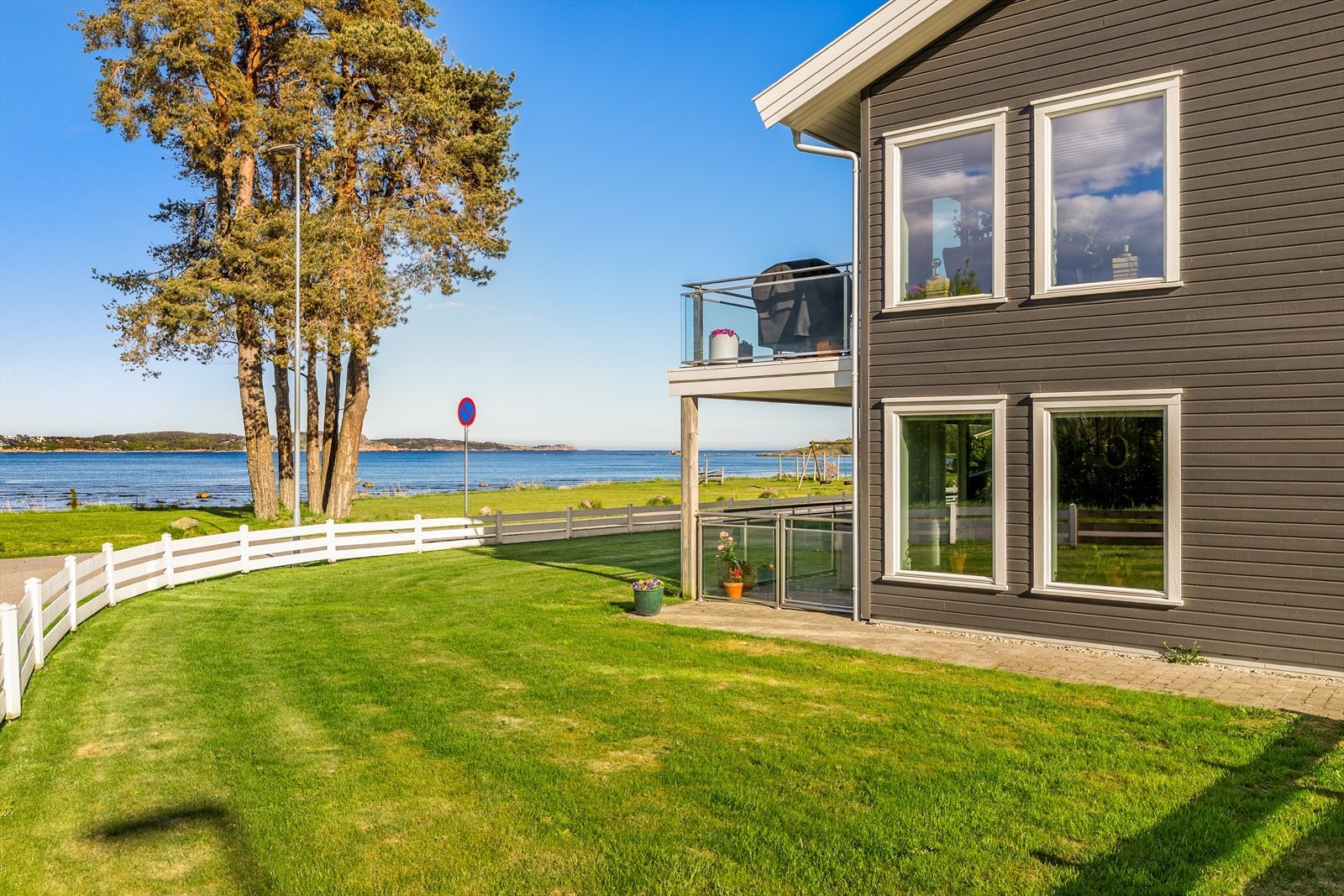 Eiendommen har en flat, felles tomt med plen og asfalterte parkeringsområder. Port fra terrassen og ut i hagen. Galleribilde