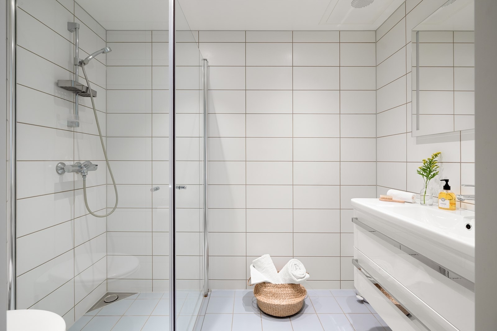 Badet har varme i gulv og er innredet med vegghengt toalett, dusjhjørne, vask i seksjon og speil med belysning. Galleribilde