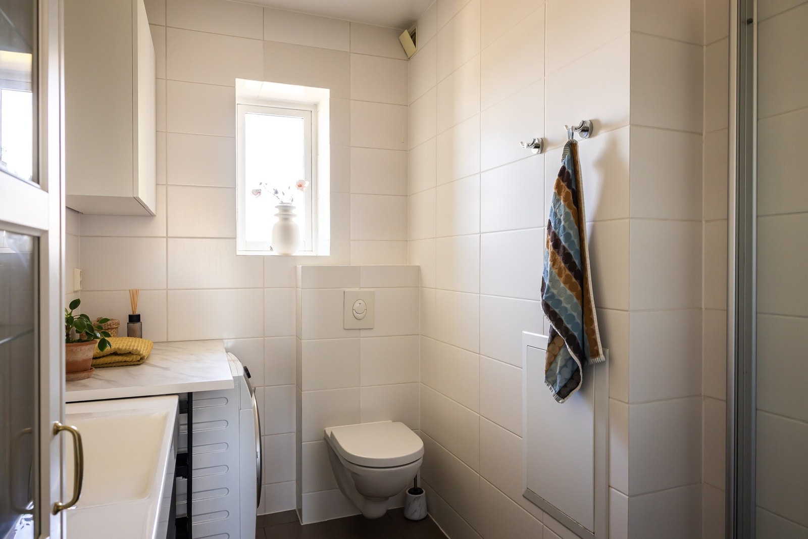 Badet er innredet med dusjnisje med innfellbare dusjdører, dusjbatteri med hånddusj og regnskogdusj, servant med ettgreps blandebatteri og underskap. Galleribilde