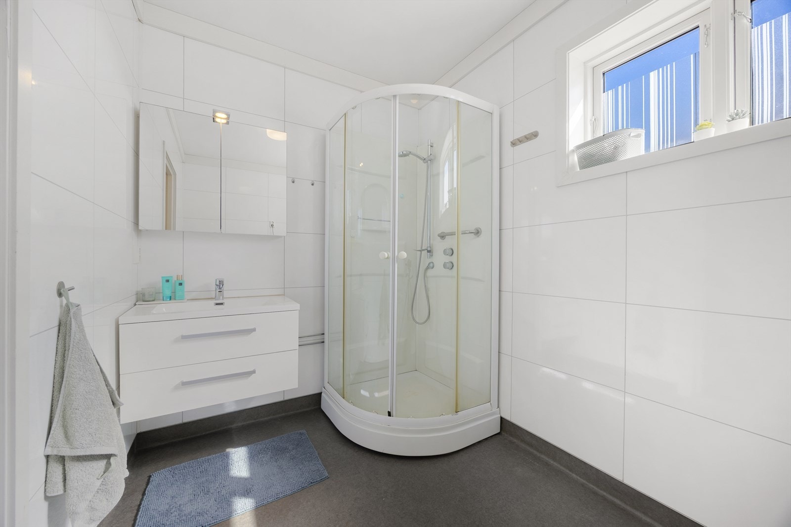 Badet i 1. etasje er fra 2017, med baderomsplater på vegg og dusjkabinett. Galleribilde