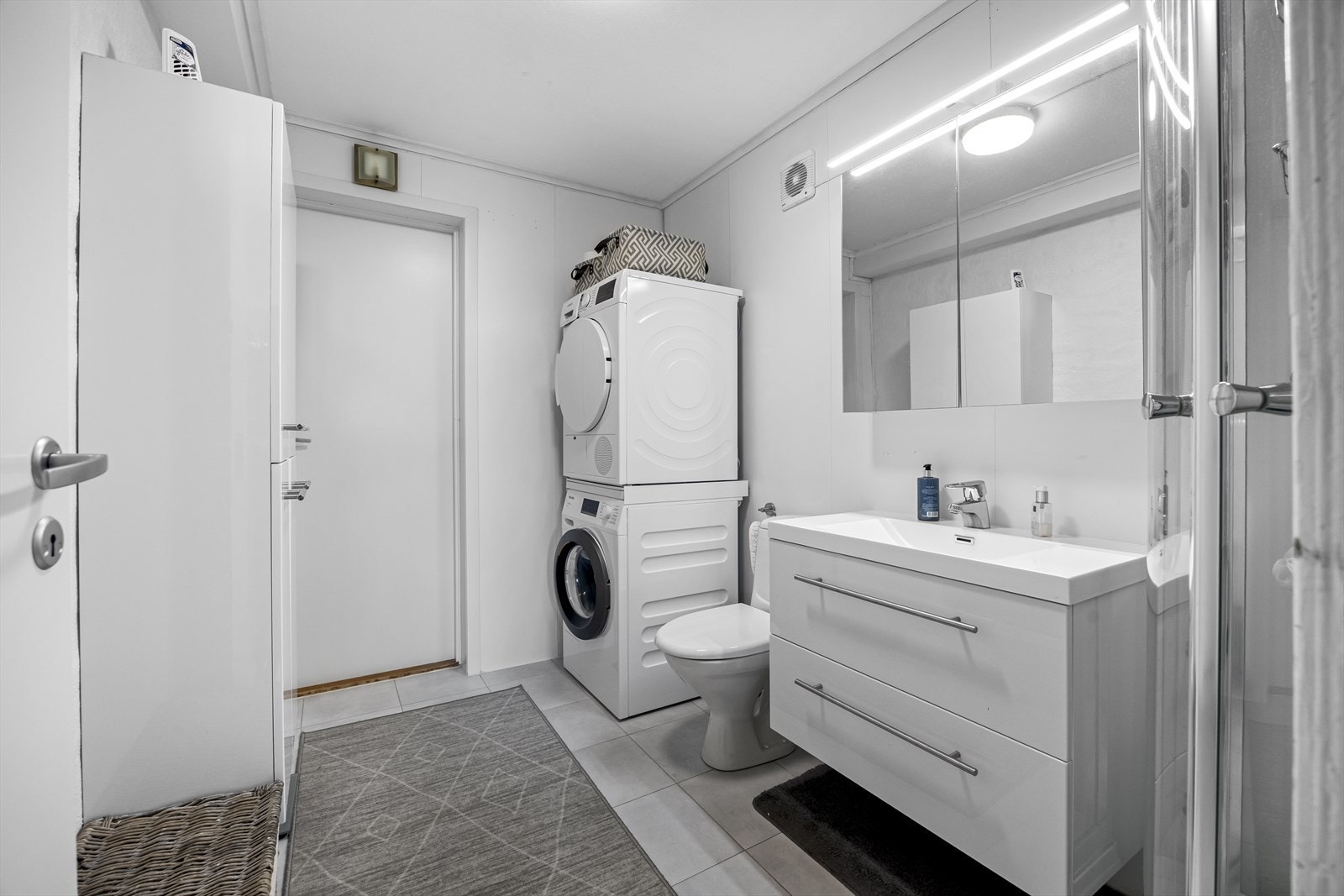 Badet i utleiedel med wc, hvit baderomsinnreding, dusjkabinett og opplegg til vaskemaskin og plass til tørketrommel over. Galleribilde