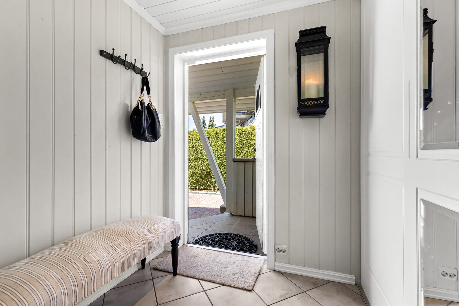 Romslig entré med flislagt gulv, mdf plater på vegger og downlights i himling Galleribilde