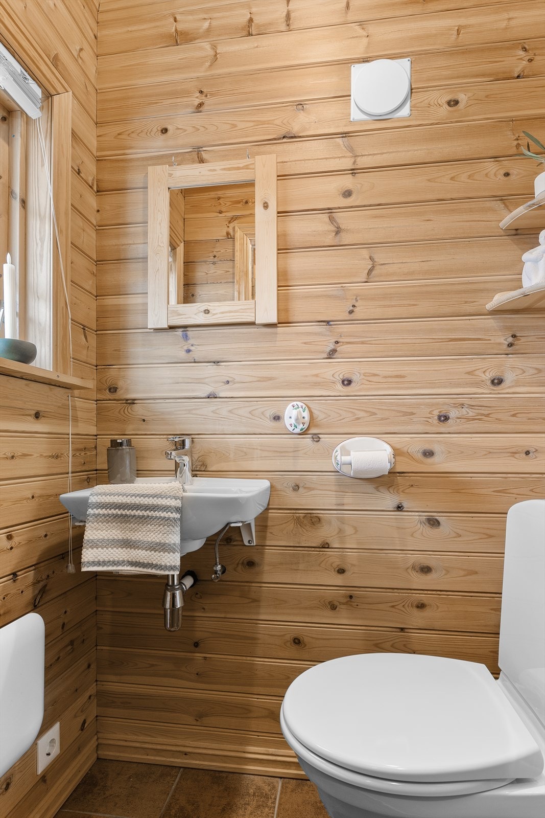 Toalettrom i første etasje med flis på gulv, panel på vegger og vegghengt servant. Galleribilde