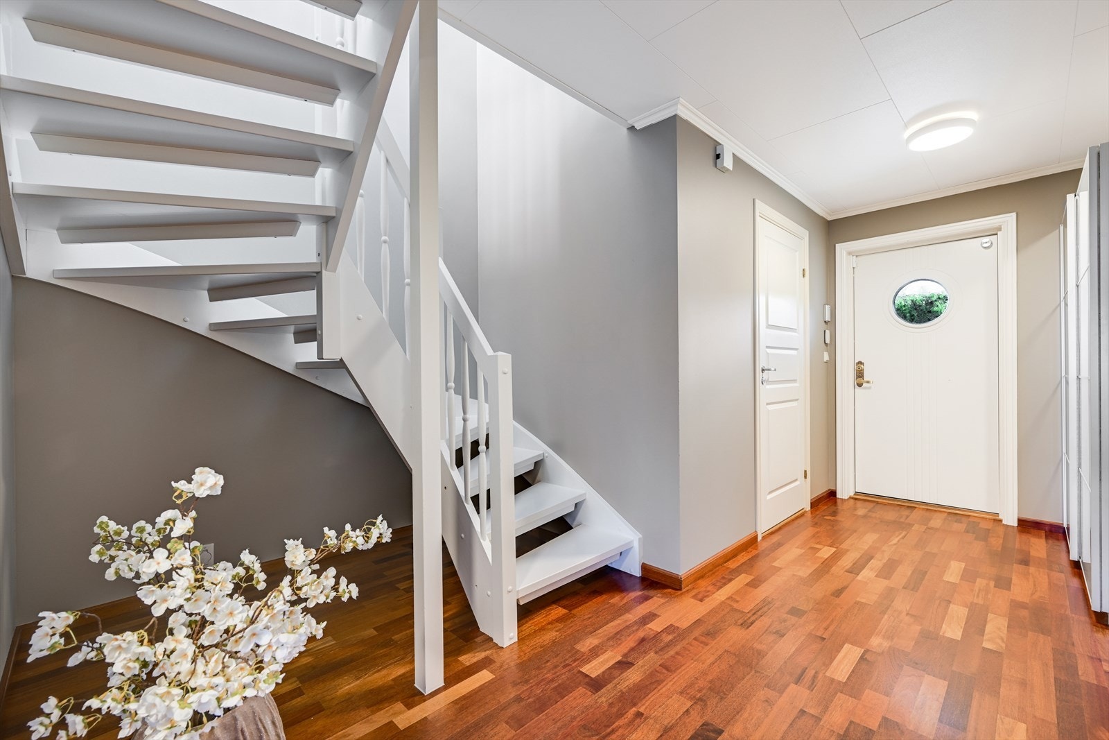 Lys og innbydende entré i første etasje med nylakkert parkettgulv. Den nymalte tretrappen forbinder boligens to plan. Galleribilde