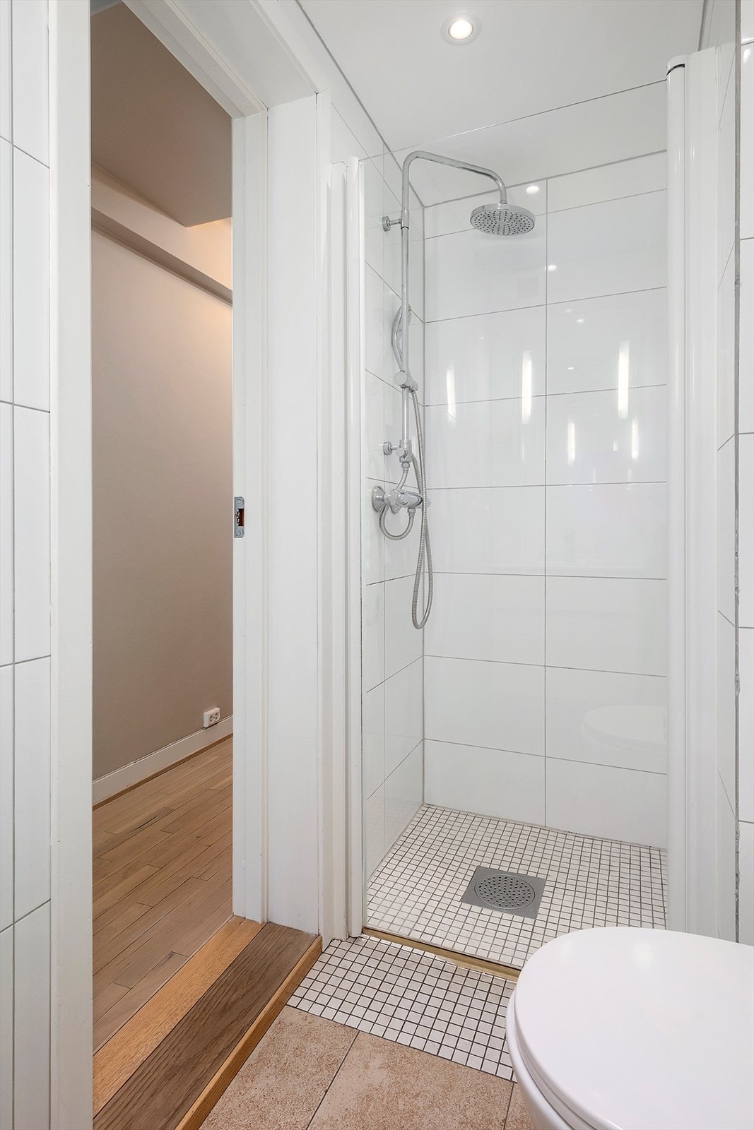 Badet er utstyrt med dusj med innfellbar dør i herdet glass, servant, veggfestet klosett med innebygget sisterne og opplegg for vaskemaskin. Galleribilde