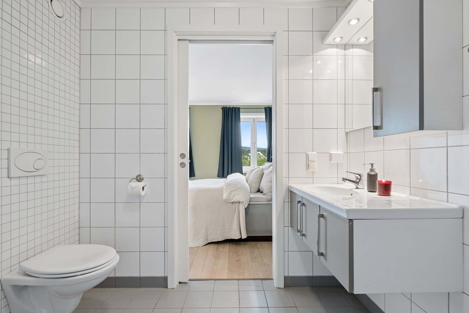 Badet har vegghengt toalett og servantinnredning med speilskap og belysning. Galleribilde