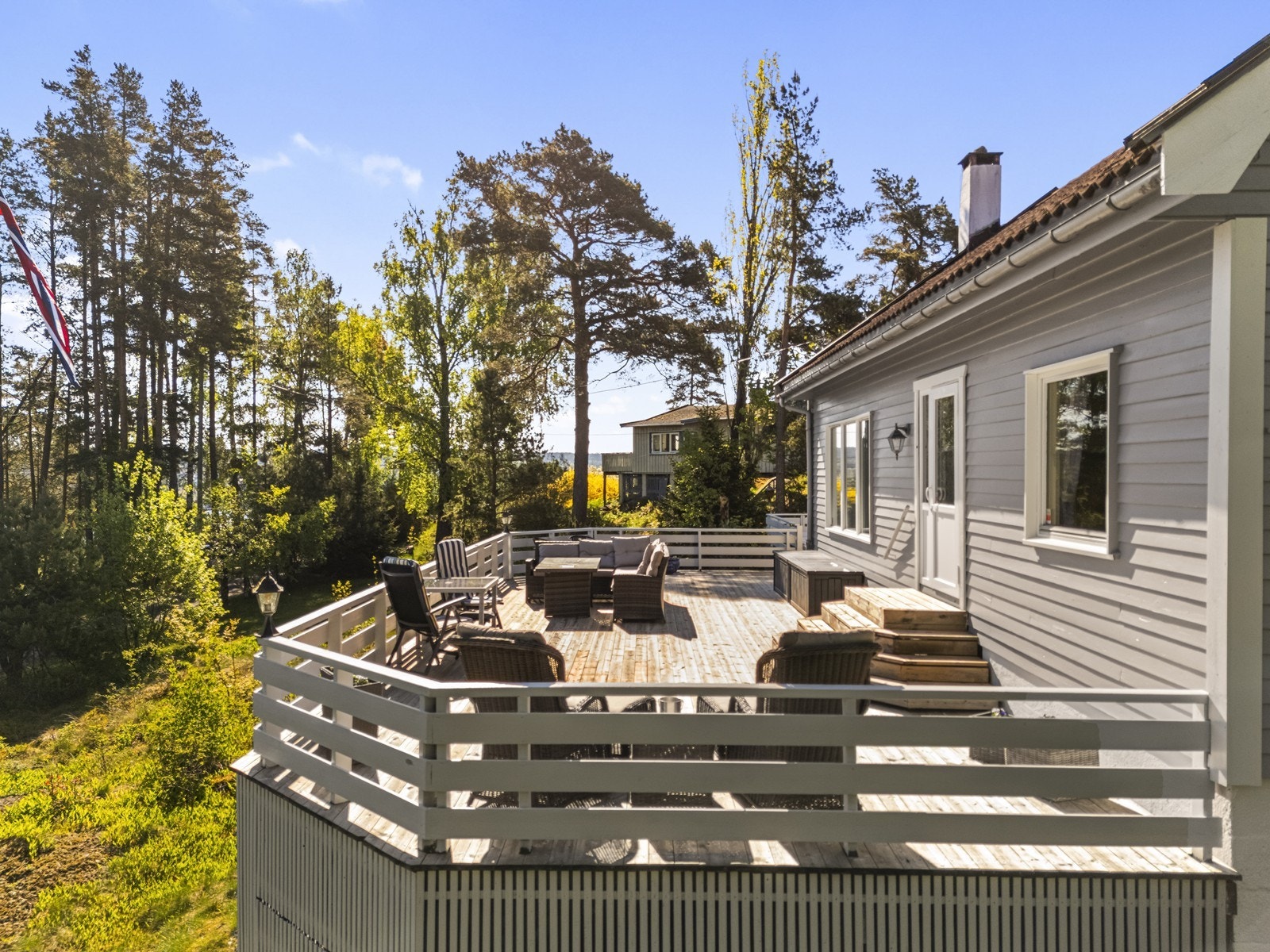 En stor treterrasse omkranser deler av boligen og gir rikelig med plass for flere sittegrupper. Galleribilde