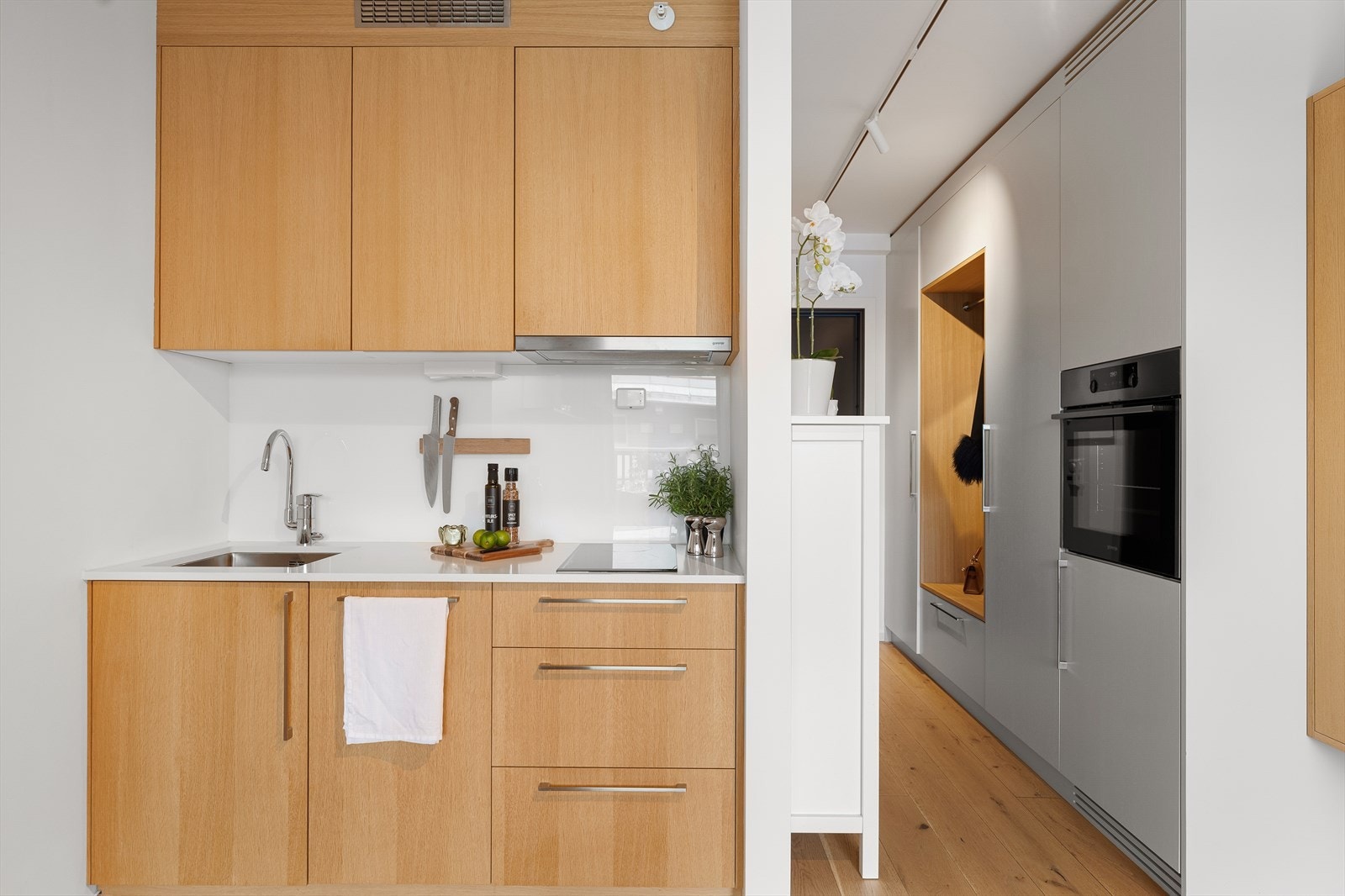 Kjøkkenet er sømløst integrert i oppholdsrommet og har et moderne og stilrent uttrykk med glatte fronter fra Blum og benkeplate i komposittmateriale. Innredningen består av både over- og underskap med gode oppbevaringsmuligheter. Galleribilde