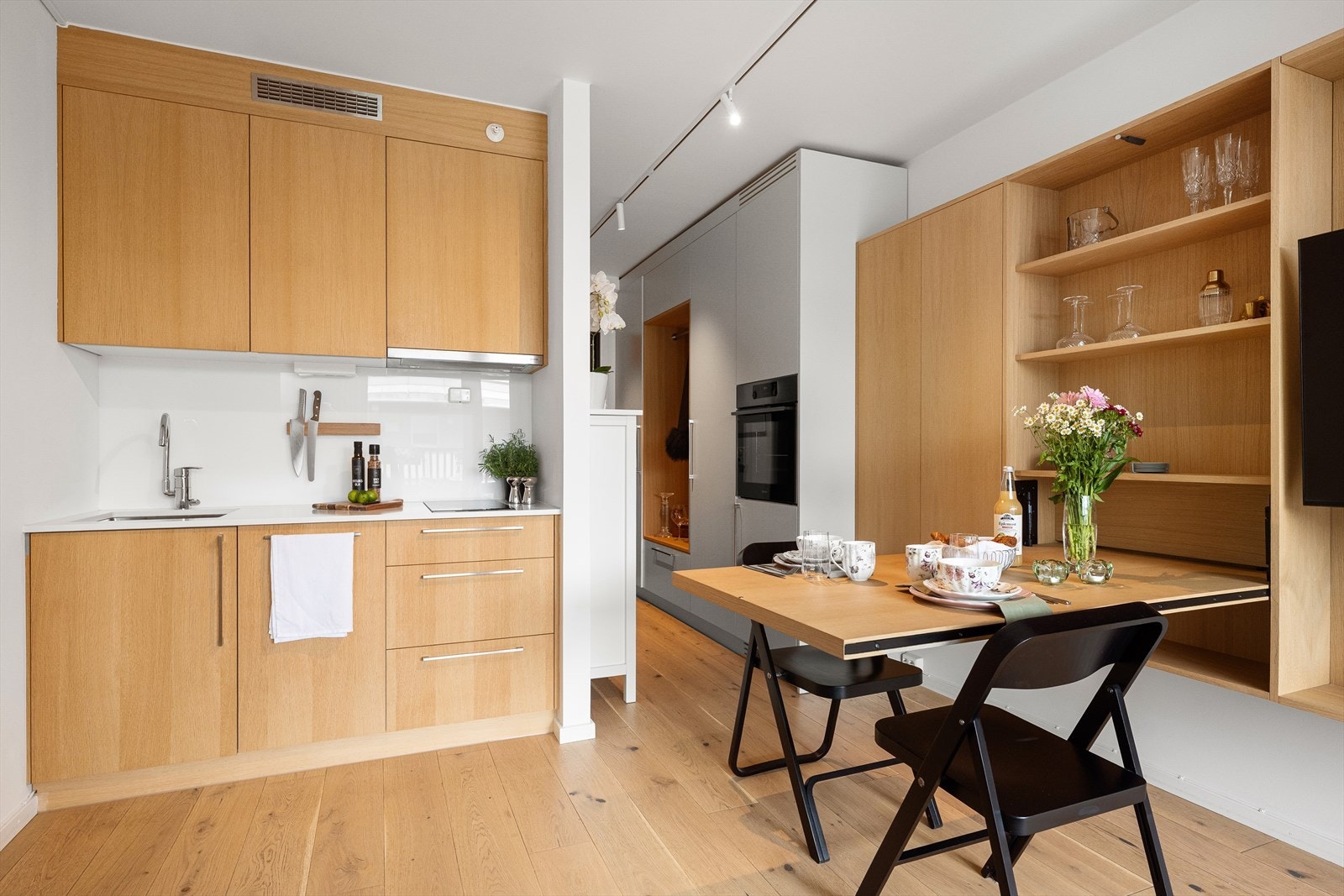 Kjøkkenet er utstyrt med integrerte hvitevarer som induksjonstopp, stekeovn, oppvaskmaskin og kjøleskap - alt elegant bygget inn for en ryddig og plassbesparende løsning. I det ene skapet er det og plassert en mindre fryser som følger med. Galleribilde