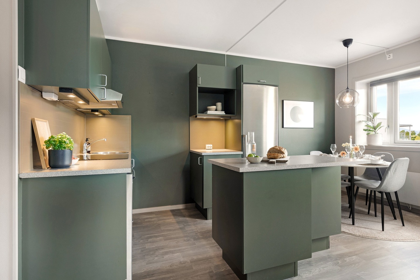 Laminatbenkeplate og benkerygg med plater gir et stilrent og praktisk uttrykk, mens belysning under overskapene bidrar til gode arbeidsforhold. Galleribilde