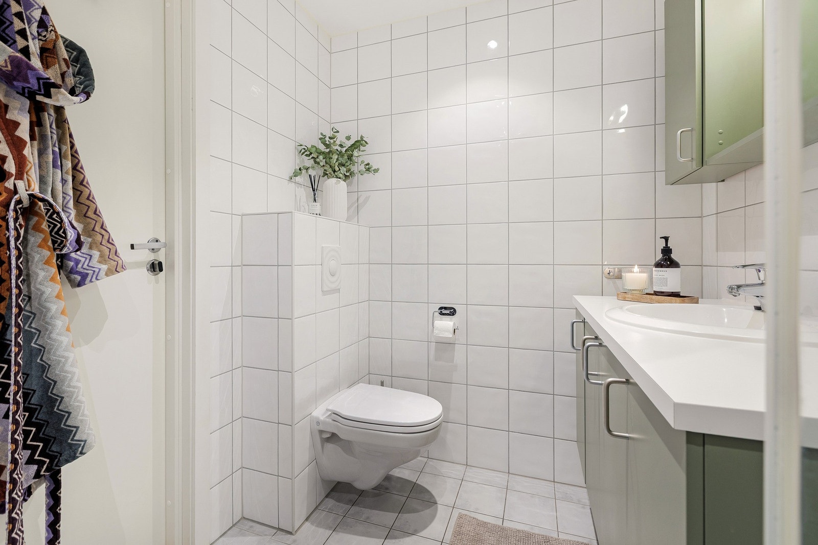 Badet er innredet med servantseksjon med nedfelt servant og skap med speil over, vegghengt toalett samt dusjløsning med glassdører. Galleribilde