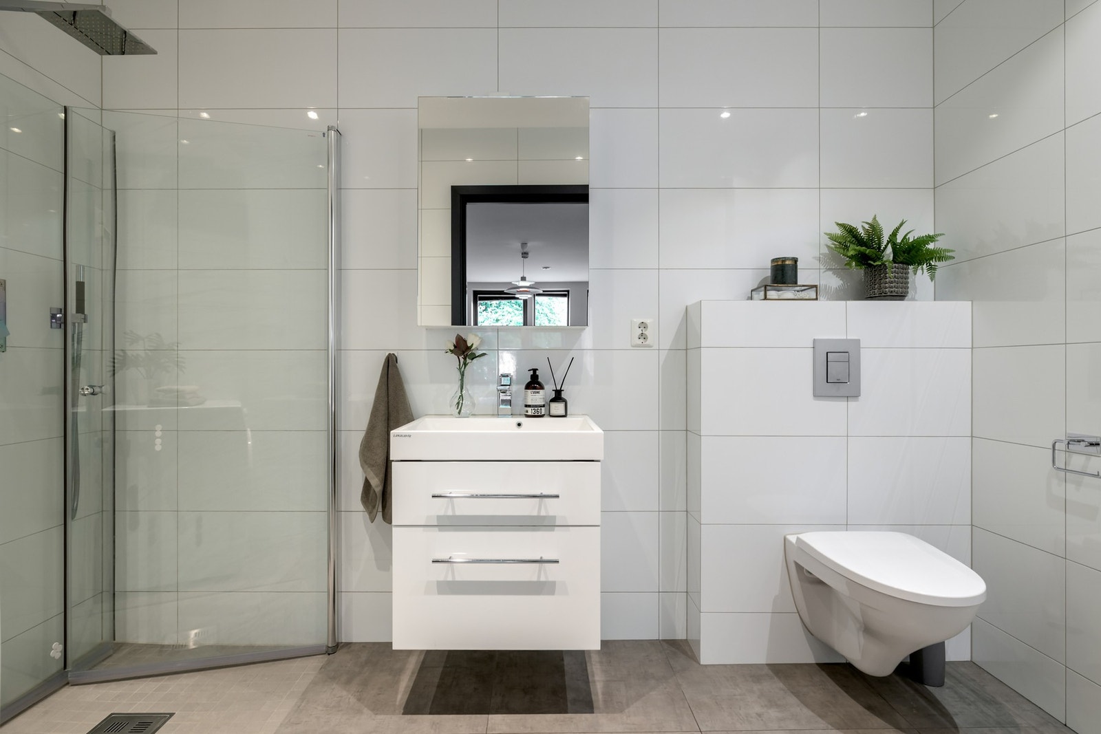 Badet er flislagt på vegger og gulv og har dusj med innfellbare, rette glassdører utstyrt med både regnfalls- og håndholdt dusj fra Tapwell Galleribilde