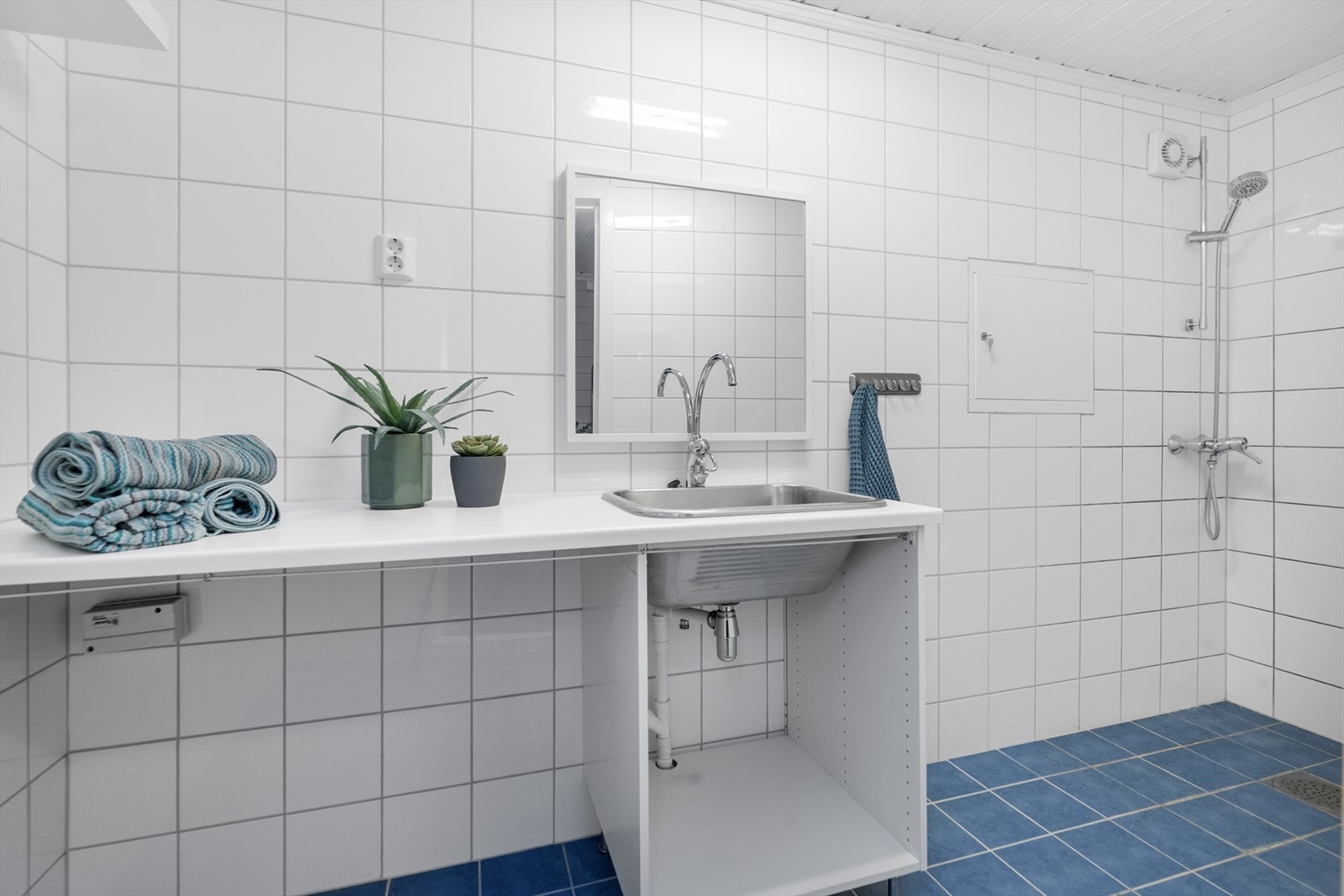 Praktisk vaskerom i underetasjen med flislagt gulv, dusj på vegg, opplegg for vaskemaskin og varmekabler i gulvet. Galleribilde